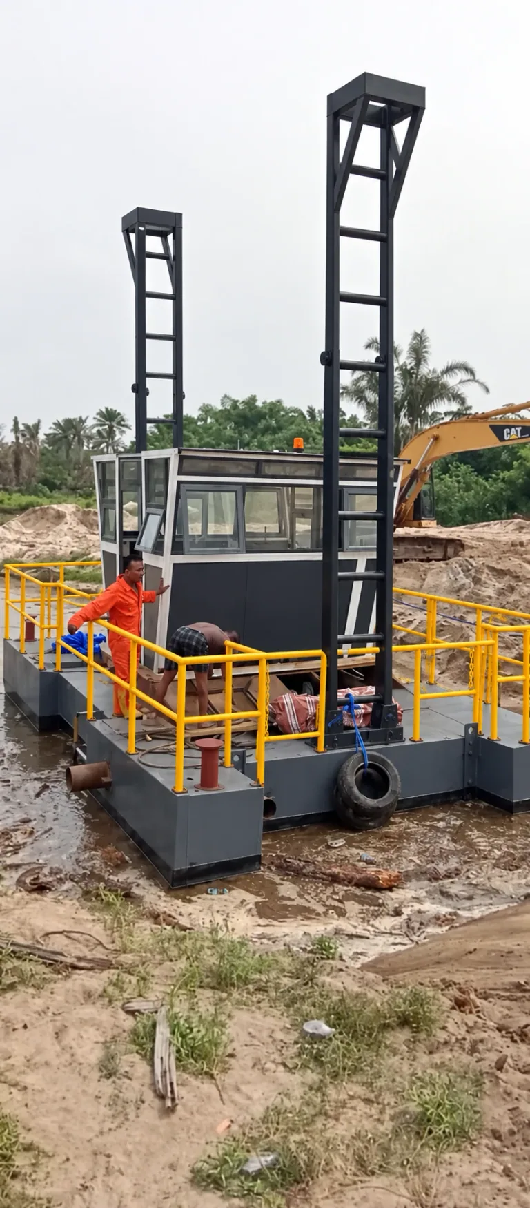 AI-enhanced company-supplied photo: Crew beside a small dredging pontoon with a cabin, upright frames and yellow rails